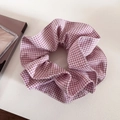 Gros plan sur un chouchou surdimensionné à carreaux rose et blanc en coton plissé doux - Rose