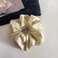 Détail d'un chouchou à fleurs jaunes sur texture blanche avec accessoires - Jaune