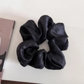 Detailed view of a large black satin scrunchie with silk texture on a minimalist background - Black