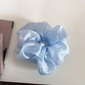 Detail of light blue pearlescent organza scrunchie with soft ruffled texture on white backdrop - Blue