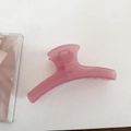 Macro shot of a translucent pink resin hair claw clip on a textured white surface - Hanger Style - Pink
