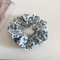 Chouchou floral avec fleurs violettes et feuilles vertes sur tissu blanc en vue de dessus - Motif Floral Bleu et Violet