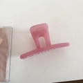 Top-down macro view of a translucent pink resin hair claw clip on white textured surface - Straight Style - Pink