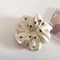 Detailopname van de beige scrunchie met stippen op een minimalistische achtergrond - Geel