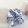 Close-up van een lichtblauwe scrunchie met zwarte stippen en zijdeachtige textuur - Blauw