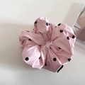 Detailweergave van de lichtroze zijden scrunchie met stippen en een zwart fashion label - Roze