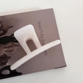 Close-up of a cream white acrylic claw clip on a magazine showing elegant hollow design - Straight Style - Beige