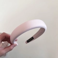 Détail d'un serre-tête en éponge rose clair rembourré avec tissu satiné et étiquette - Rose