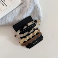Detail von drei Acetat-Haarspangen mit Marmortextur auf schwarzer Karte im Wellendesign - Schildpatt Braun