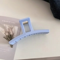 Close-up of light blue matte hair claw clip with spring detail on denim background - Bar Style / Creamy Blue