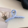 Close-up of a light blue glossy shark hair claw clip with strong metal spring detail - Crossed / Creamy Blue