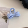 Detail of light blue bow-shaped hair claw clip with metallic spring on a white surface - Ribbon Bowknot / Creamy Blue