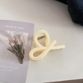 Detailed 45-degree angle view of a cream-colored twist hair claw clip on a desk - Twist Knot Style / Milk Yellow