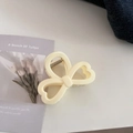 Detail view of the cream-colored bow hair claw clip with a stylish hollow heart pattern - Heart Bow Style / Creamy Yellow