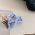 Detail view of light blue resin hair claw clip with bow design and heart cutouts - Heart Bow Style / Creamy Blue