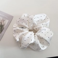 Satijnen scrunchie met stippen en logo naast een decoratieve tulpenkaart - Broken Wit