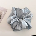 Macro-detail van een lichtblauwe satijnen scrunchie met stippen en zijden textuur - Blauw