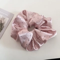 Detail van de roze satijnen scrunchie met stippen en zijdeglans op een crème ondergrond - Roze