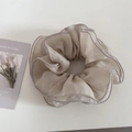 Detail of oversized checkered scrunchie with layered ruffles and soft chiffon fabric texture - Apricot