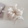 Détail d'un chouchou en tulle blanc avec de longs rubans sur fond minimaliste doux - Blanc Cassé