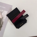Close-up of elegant acetate hair clips in red and black on a minimalist paper display - Red Black