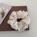 Close-up of beige cotton linen scrunchie with delicate floral embroidery on dark wood - Beige Pleated Style