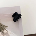 Detailed view of a glossy black acetate hair claw clip with a secure interlocking tooth design - Black