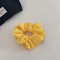Detailed texture of a bright yellow cotton scrunchie with a side label and denim accent - Yellow