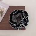 Dettaglio di uno scrunchie patchwork a scacchi con bordo in pizzo bianco su legno - Nero