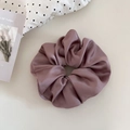 Close-up of elegant dusty pink satin scrunchie with silky folds and soft texture details - Pink