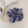 Detailed macro view of gray-blue satin scrunchie showing glossy fabric texture and pleats - Blue