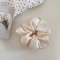 Detail of cream oversized satin scrunchie with rich pleats on minimalist aesthetic background - Beige