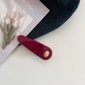 Detailansicht der dunkelroten Haarspange mit Goldlogo auf blauem Denim und weißer Karte - Rot
