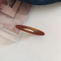 Close-up of amber-colored acetate hair clip with hollow oval design and metal spring clip - 3# Caramel Brown