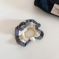 Dettaglio di un elastico per capelli crema con bordo a quadretti e grande perla lucida - Beige