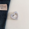 Dettaglio macro di un fermaglio per capelli in acetato a cuore con scritta e clip in metallo - Bianco Sirena