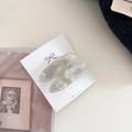 Close-up of oval iridescent resin hair clips with gold lettering on white card - Pearlescent White Marble