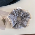 Detail eines hellvioletten Blumen-Haargummis mit Spitzenrand im Vintage-Landhausstil - Grau