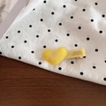Detailed macro view of a yellow acetate heart hair clip on a polka dot background - Yellow