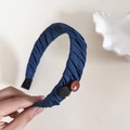 Detaillierte Nahaufnahme des blauen Falten-Stirnbands mit Holzknopf und handgefertigtem Etikett - Hellblaues Stirnband