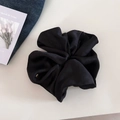 Detail of a large black satin scrunchie with a gold metal tag on a clean white background - Black