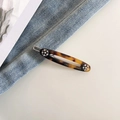 Detailed close-up of tortoise shell oval hair clip with gold engraving and rhinestones - Dark Tortoiseshell