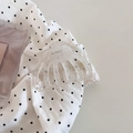 Detail einer minimalistischen, klaren Haarklammer auf einem gepunkteten Stoffhintergrund - Weiß