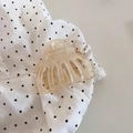 Detail der pfirsichfarbenen Haarspange mit goldener Metallfeder auf gepunktetem Stoff - Aprikose
