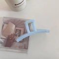 Détail d'une pince à cheveux mate bleu clair avec ressort doré sur une table blanche - Bleu