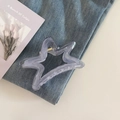 Primer plano de una pinza para el cabello en forma de estrella lila sobre denim - Gris