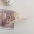 Détail d'une pince à cheveux carrée marbrée beige à côté d'une tasse à café en céramique - Abricot