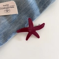 Macro view of a glossy wine red starfish hair clip with a silver metal spring back - Red