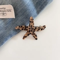 Detailed view of a tortoiseshell starfish hair clip with metal spring on denim fabric - Brown Polka Dot
