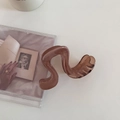 Detailed view of translucent amber wave hair claw clip on minimalist white background - Coffee